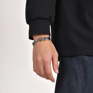 Detailed close-up of a vintage feather-shaped open cuff bracelet worn on the wrist