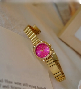 Detail of vintage gold watch with vibrant rose pink dial and elegant radial texture
