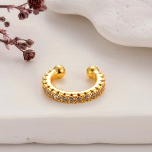 Elegant gold micro-pave zircon ear cuff on white stone with dry floral decor