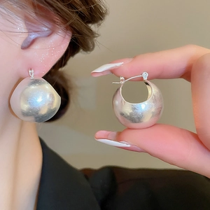 Macro shot of silver U-shaped chunky hoop earrings with a brushed metal matte finish