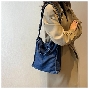 Detail of blue denim tote bag showing its side metal buckle and large capacity