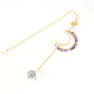 Macro detail of moon sun pendant with purple gravel crystals and clear faceted glass ball
