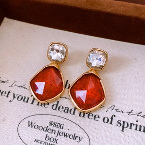 Macro detail of geometric resin earring with red amber hue and gold-plated metal borders