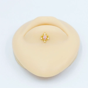 Détail d'un piercing nombril couronne avec gemme rose en forme de goutte sur modèle