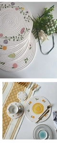 Detailed view of round woven cotton placemats with colorful floral and fruit embroidery