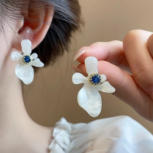 Eleganti orecchini a fiore in resina bianca con zircone blu e dettagli dorati