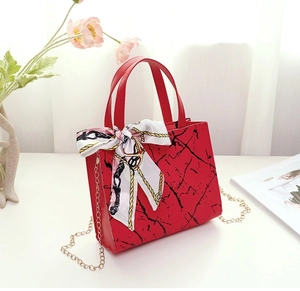 Detail view of red marble pattern tote bag with silk scarf and gold chain strap