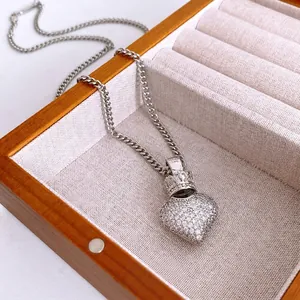 Silver crown heart pendant necklace with shimmering zircon stones on a wooden jewelry display