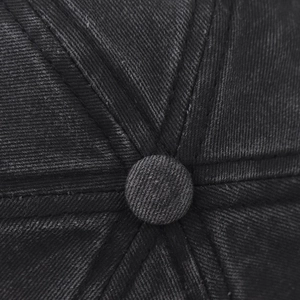 Macro detail of the top button and stitched seams on a washed grey cotton baseball cap