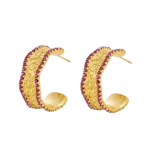 Macro detail of gold hammered metal earrings with magenta pavé crystals and wavy design