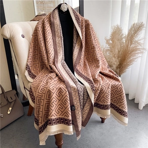 Detail of soft brown and beige cashmere-like scarf with Greek key pattern and tassels