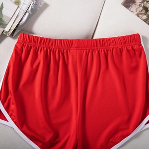 Detail of red athletic shorts with white trim and wide elastic waistband on fabric