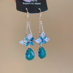 Detailed view of floral tassel earrings with blue crystals and green teardrop stone