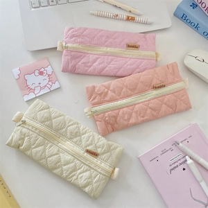Pastel quilted pencil cases in pink and beige on a desk with stationery accessories