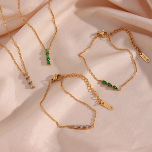 Close-up of 18K gold-plated jewelry set featuring emerald and clear teardrop gemstones