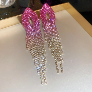 Macro shot of pink gold gradient tassel earrings with crystals on a metallic tray