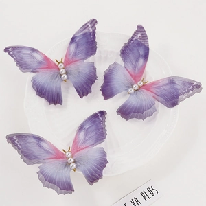 Three gradient purple gauze butterfly hair clips with pearls on a white decorative plate