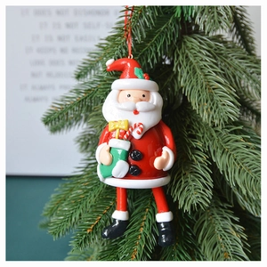 Close-up of Santa Claus ornament hanging on green pine needles with red hanging cord