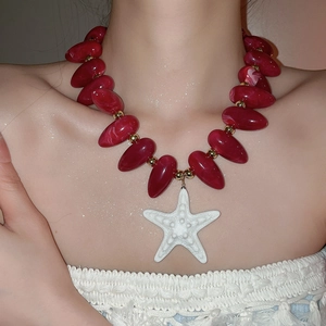 Nahaufnahme der roten Acryl-Perlenkette mit weißem Seestern-Anhänger am Model