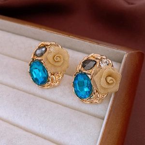Macro shot of vintage gold flower earrings with blue and black gemstones on velvet