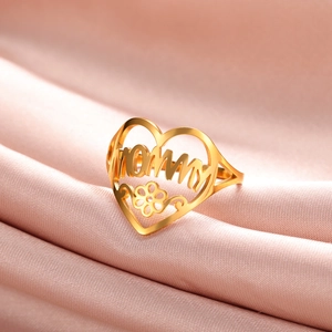Golden open heart ring featuring hollow MOMMY text and flower detail on pink silk