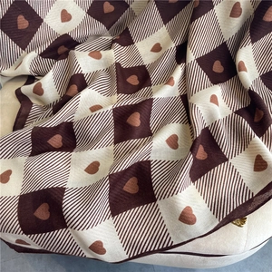 Close-up detail of checkered cotton linen scarf with heart patterns and soft texture