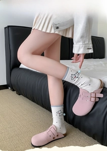 Pink suede mule sandals paired with white cartoon dog print socks and blue pom-pom details