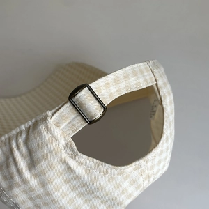 Detail of checkered baseball cap back with adjustable bronze metal buckle strap