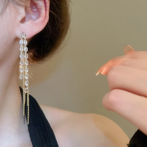 Close-up of elegant gold tassel earrings with zircon crystals on a female model