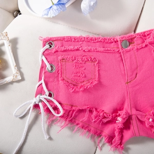 Dettaglio di pantaloncini di jeans rosa con lacci laterali e orli sfrangiati