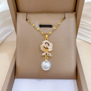 Detail of royal style gold necklace with white rose pendant and hanging pearl charm