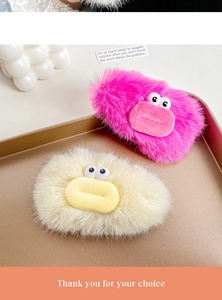 Detailed view of pink and beige plush hair clips with cartoon eyes on a golden tray