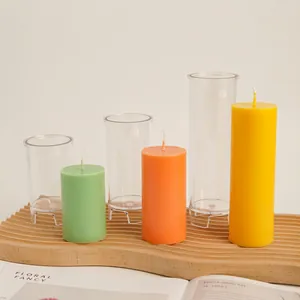 Three transparent cylindrical candle molds in varying heights on a wooden wave tray
