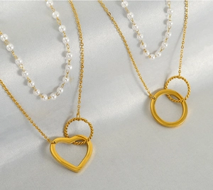 Détail d'un collier de perles doré double couche avec pendentifs cœur et anneaux entrelacés