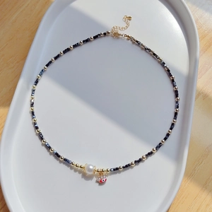 Collier perles d'eau douce avec pendentif mauvais œil et perles cristal noir sur plateau