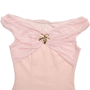 Detail eines rosa trägerlosen Kleides mit Netzfalten und goldener Blumenbrosche