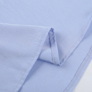 Macro shot of light blue satin dress fabric showing premium stitching and woven texture