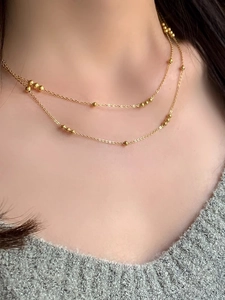Close-up of double-layered gold beaded necklace on model showing elegant layering effect