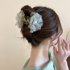 Gros plan d'une pince à cheveux élégante avec fleurs en dentelle et perles sur chignon
