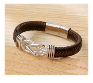 Detail of hand-woven dark brown leather bracelet with silver magnetic knot clasp on wood