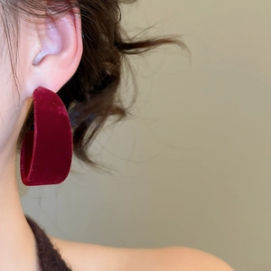Gros plan d'un mannequin portant une boucle d'oreille en velours rouge foncé en forme de C