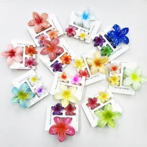 Detailed close-up of colorful gradient plumeria flower hair claws in a three-piece set