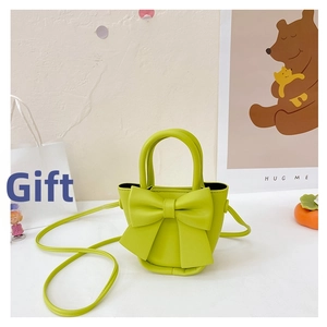 Macro shot of a grass green kids crossbody bag featuring a large bow detail and PU texture