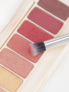 Detail of a 6-color eyeshadow palette with champagne and bronze tones and a soft brush