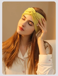 Close-up of a soft yellow knotted headband worn by a model in a cozy home setting