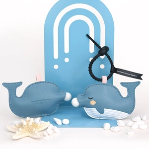 Whale PU leather keychain set with black beads and ribbon on a soft blue background