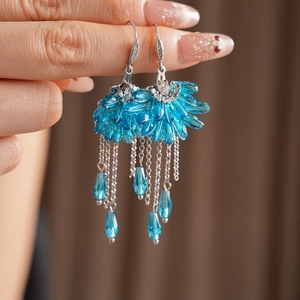 Détail de boucles d'oreilles bohèmes en forme d'éventail avec perles bleues et glands