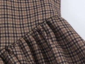 Detailed macro view of the brown plaid fabric texture and ruffled stitching of the dress