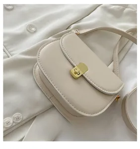 Detail of elegant cream saddle bag with a rectangular gold buckle on a matching blazer