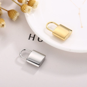 Detailed view of gold and silver stainless steel padlock pendants on a textured surface
